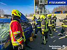 Gruppe von THW und Feuerwehr vor einem PKW zur Demonstration