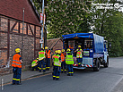 Gruppe Einsatzkräfte hinter einem Fernmeldekraftwagen beim Kabelbau