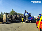 Ausgebrannter LKW-Anhänger mit Bagger des THW und Feuerwehr-Fahrzeug